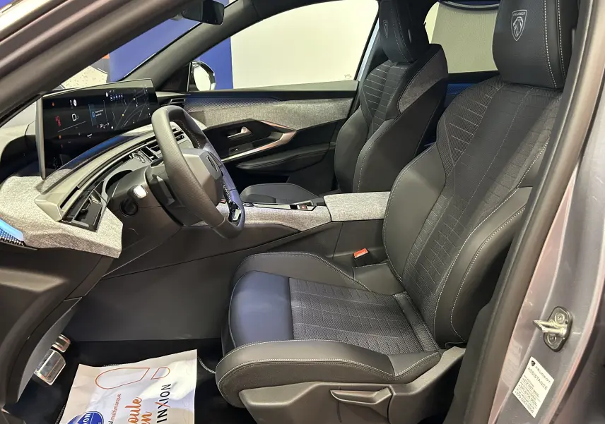 Vue intérieure côté conducteur du Peugeot 5008 III GT Hybrid 145 avec sièges noirs et tableau de bord moderne gris Artense.