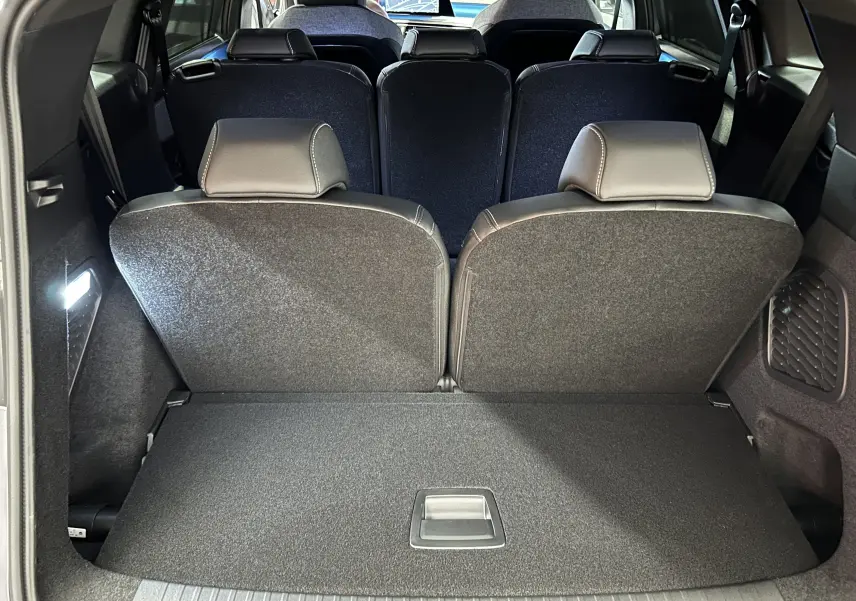 Coffre ouvert montrant la troisième rangée de sièges rabattus du Peugeot 5008 gris Artense, vue arrière intérieure.