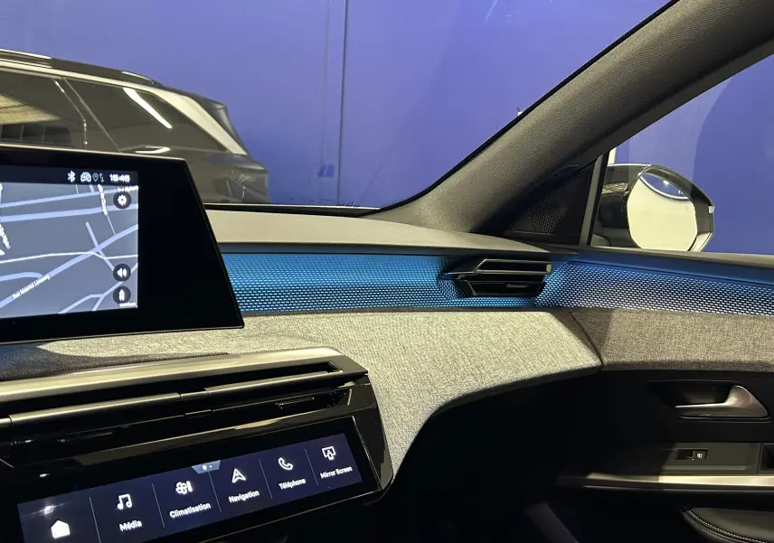 Intérieur du Peugeot 5008 III GT Hybrid 145, vue côté passager avec tableau de bord gris et éclairage bleu ambiance.