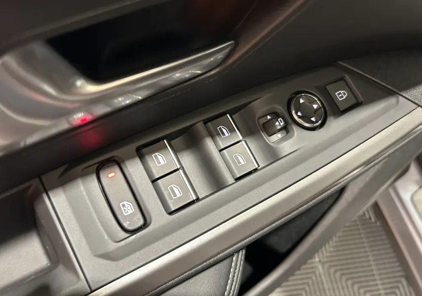 Gros plan sur les commandes des vitres et rétroviseurs côté conducteur du Peugeot 5008 gris Artense 2025.