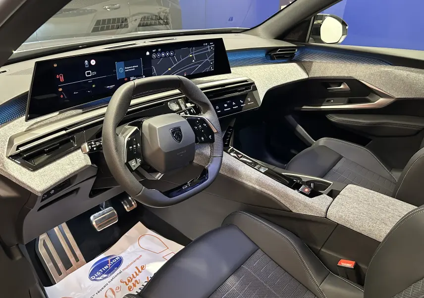 Intérieur avant droit du Peugeot 5008 III GT Hybrid 145 avec tableau de bord numérique et sellerie noire et grise.