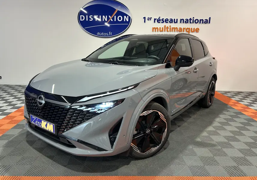 Nissan Qashqai gris céramique métal en 3/4 avant droit, avec jantes noires et toit panoramique visible.