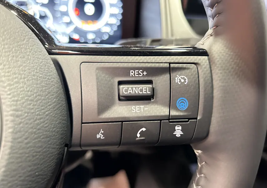 Gros plan sur les commandes de régulateur de vitesse au volant noir du Nissan Qashqai gris céramique 2025.