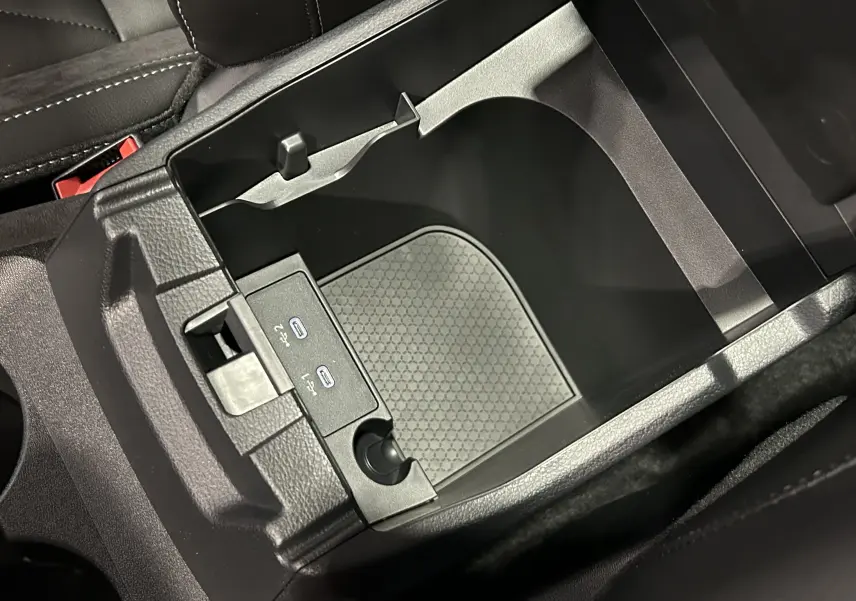 Gros plan sur la console centrale noire du Nissan Qashqai 2025 avec ports USB-C et rangement intérieur.