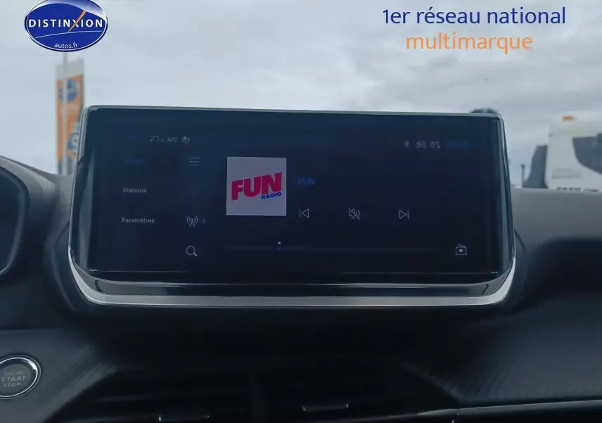 Écran tactile central allumé sur radio FUN dans l’habitacle d’une Peugeot 2008 rouge Elixir, vue de face.