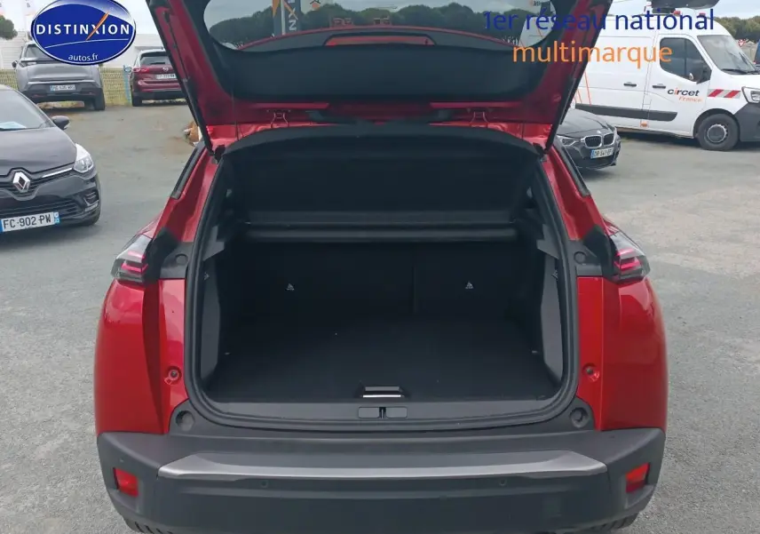 Coffre ouvert d’un Peugeot 2008 rouge elixir vu de l’arrière, montrant l’espace de chargement vide.
