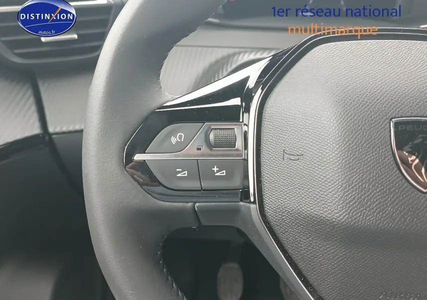 Gros plan sur le volant noir de la Peugeot 2008 1.2 100 allure, avec commandes intégrées côté gauche.
