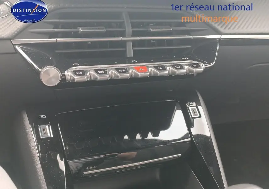 Vue rapprochée de la console centrale noire brillante du Peugeot 2008 1.2 100 allure, avec commandes et aérateurs visibles.