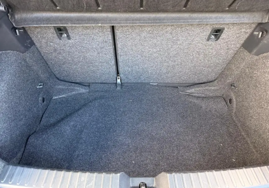 Coffre vide de la SEAT IBIZA 1.0 TSI 95 FR 2025, vue intérieure montrant la moquette grise foncée et les fixations arrière.