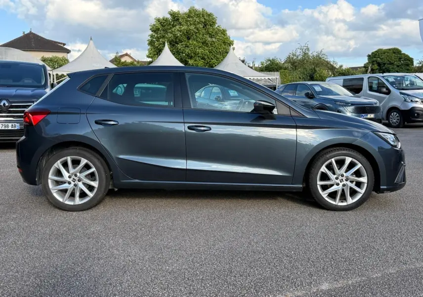 Vue de profil côté gauche d'une SEAT Ibiza 1.0 TSI 95 FR gris foncé avec jantes alliage et lignes dynamiques.