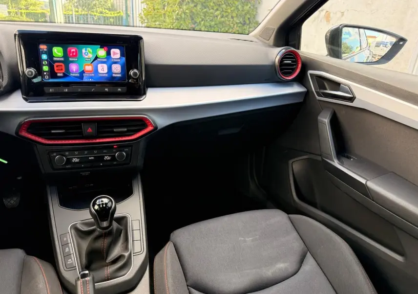 Intérieur de la SEAT Ibiza 1.0 TSI 95 FR 2025, vue côté passager, tableau de bord gris avec touches rouges et écran tactile.
