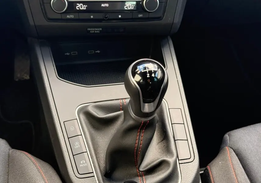 Le levier de vitesse manuel noir avec surpiqûres rouges dans l'habitacle d'une SEAT IBIZA gris foncé 2025.