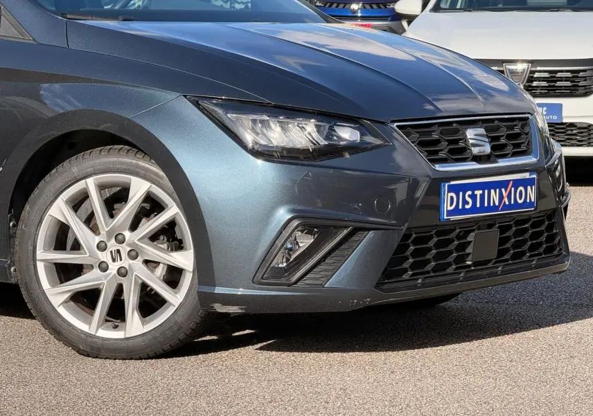 Vue 3/4 avant gauche d'une SEAT Ibiza 1.0 TSI 95 FR gris foncé avec jantes alliage et calandre hexagonale noire.