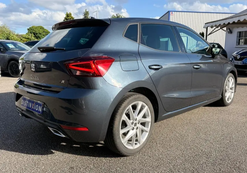 Vue 3/4 arrière droite d'une SEAT Ibiza 1.0 TSI 95 FR gris foncé avec jantes alliage et feux LED distinctifs.