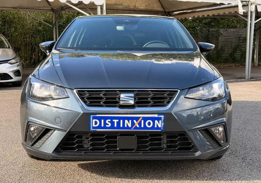 Vue frontale d'une SEAT Ibiza 1.0 TSI 95 FR gris foncé avec calandre noire et phares LED allumés.