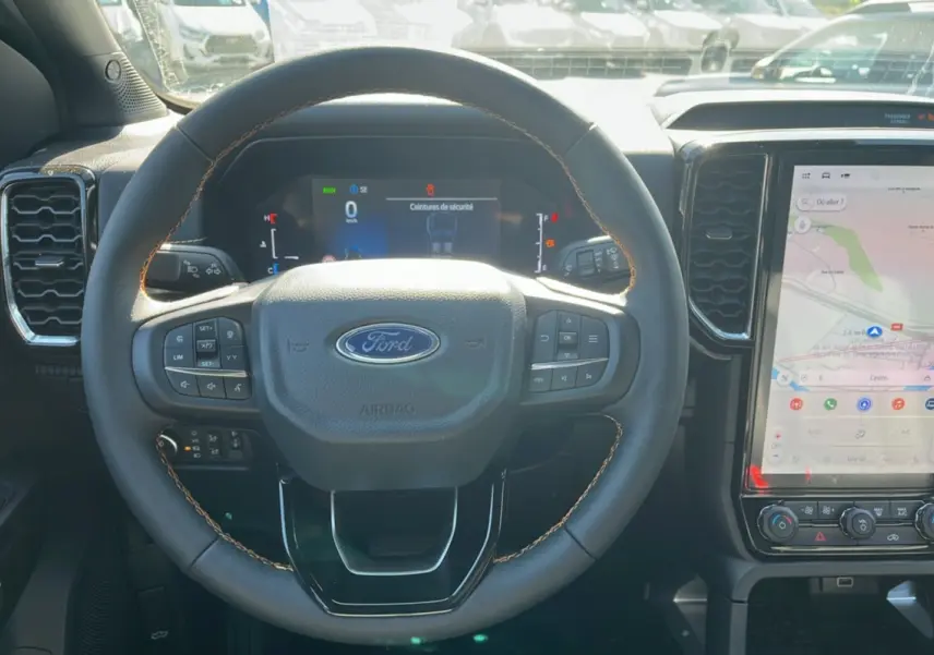 Vue intérieure centrée sur le volant du Ford Ranger 2025 gris carbone avec écran numérique et grand écran tactile.