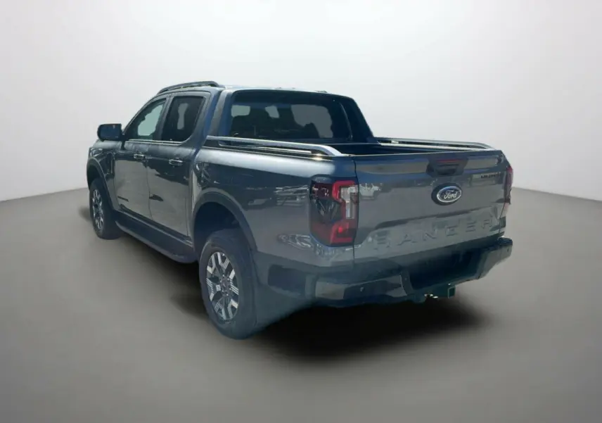 Ford Ranger 2.3 PHEV 281 Wildtrak Plus gris carbone, vue 3/4 arrière côté gauche avec benne ouverte.