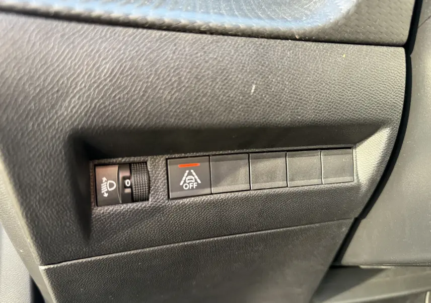 Gros plan sur les commandes de réglage des phares et désactivation de l'alerte de franchissement de ligne dans une Peugeot 2008.