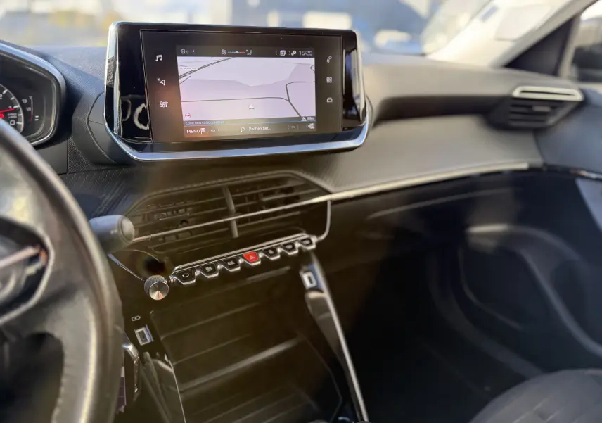 Vue intérieure du tableau de bord et écran tactile du Peugeot 2008 gris 1.5 HDi 100 Active de 2020 avec commandes tactiles et volant partiel visible.