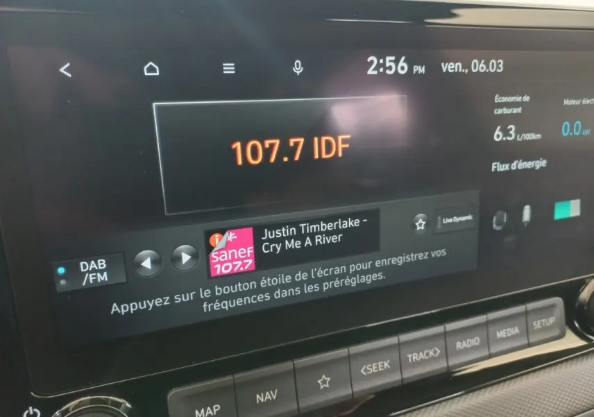 Écran tactile central du tableau de bord du Hyundai Kona gris foncé, affichant radio et données de consommation.
