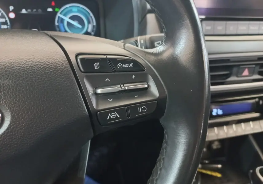 Gros plan sur le volant cuir noir côté gauche du Hyundai Kona 2022 avec commandes multifonctions visibles.
