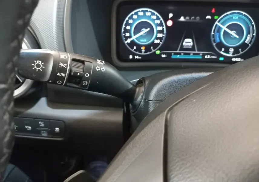 Vue rapprochée du tableau de bord numérique et du commodo d'éclairage du Hyundai Kona hybride 2022, intérieur noir.