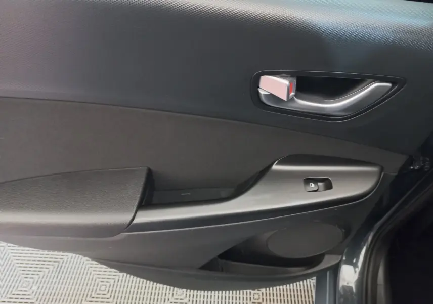 Gros plan sur la porte avant droite grise foncée du Hyundai Kona 2022, avec poignée intérieure argentée et commande de vitre.