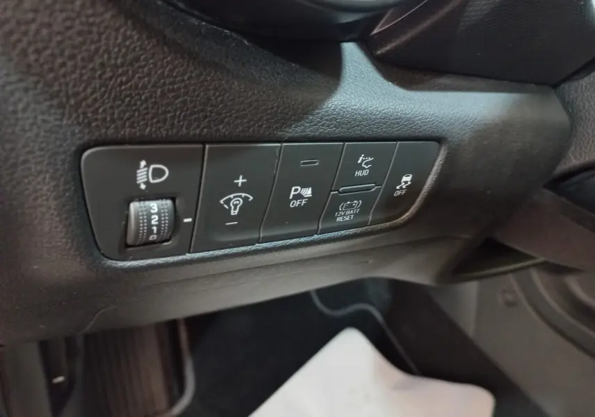 Gros plan sur les commandes de réglage des phares et aides à la conduite côté conducteur du Hyundai Kona gris foncé 2022.