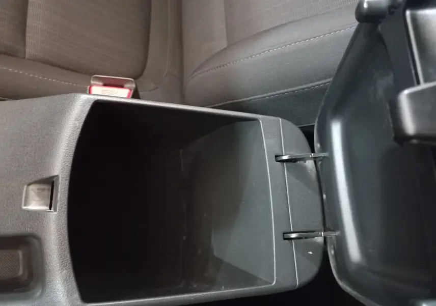 Vue rapprochée de la console centrale ouverte avec rangement intérieur, sièges tissu gris foncé Hyundai Kona 2022.