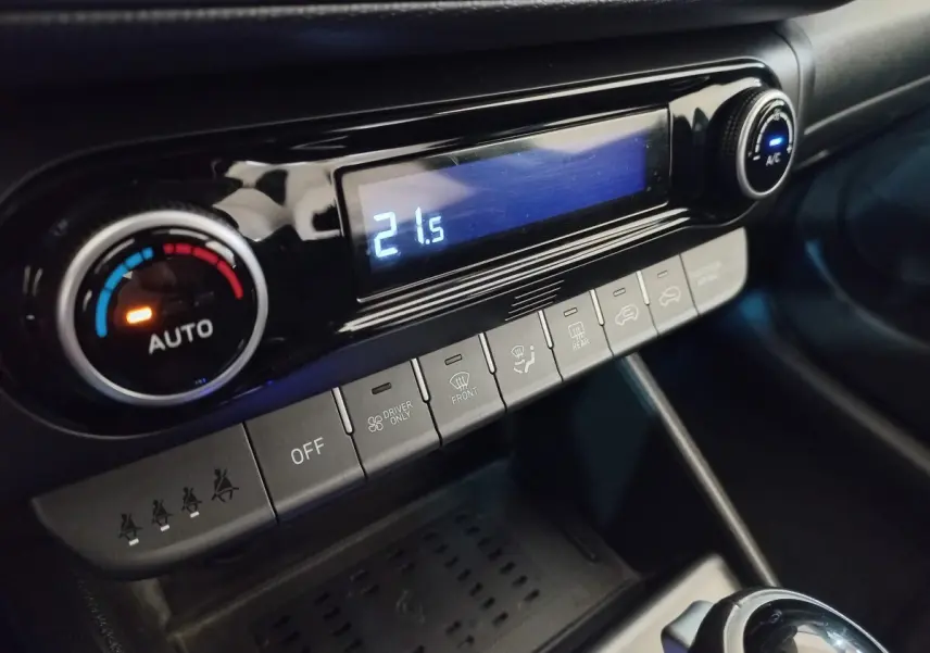 Gros plan sur la console centrale noire du Hyundai Kona 2022, affichant la climatisation à 21,5°C avec commandes tactiles.