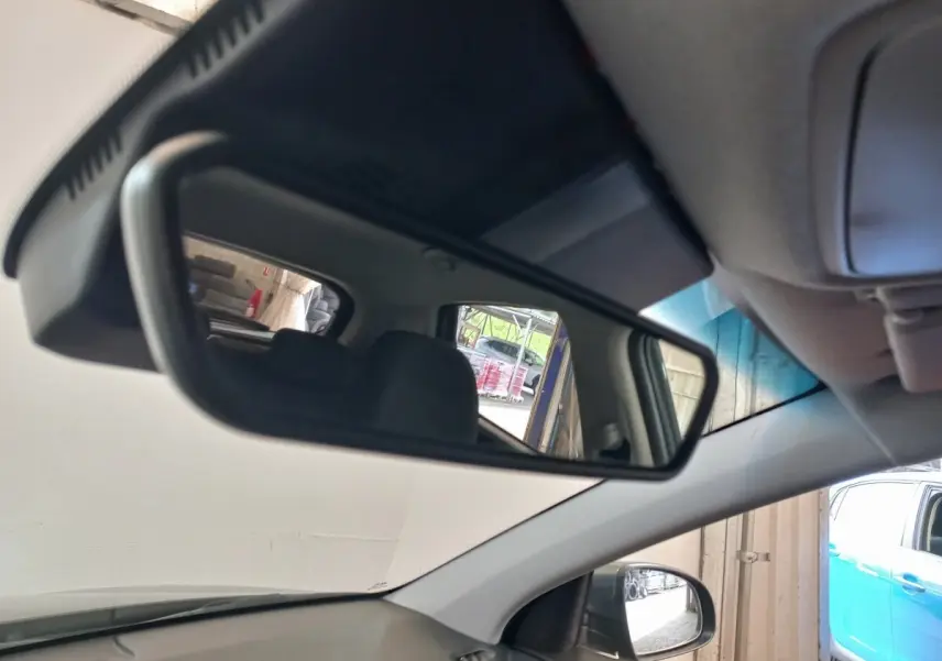 Vue intérieure du rétroviseur central du Hyundai Kona gris foncé, avec siège arrière et extérieur partiel visibles.