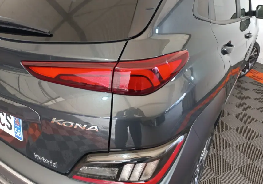 Vue arrière côté droit d'un Hyundai Kona gris foncé avec feux arrière LED et badges "KONA" et "hybrid" visibles.