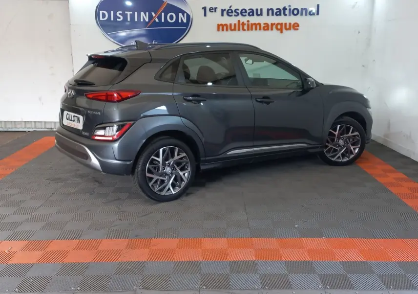 Vue 3/4 arrière droite d'un Hyundai Kona gris foncé avec jantes alliage et feux arrière LED, en intérieur showroom.