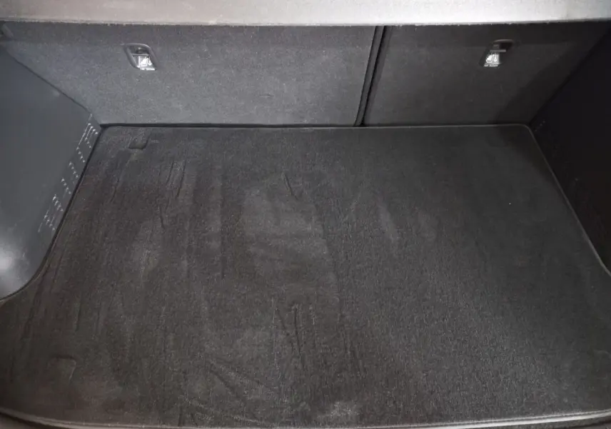 Vue plongeante sur le coffre spacieux et propre du Hyundai Kona 1.6 Hybrid 2022, avec tapis de sol noir.