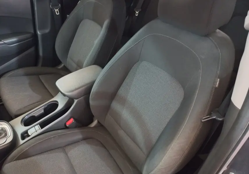 Gros plan sur les sièges avant gris foncé de la Hyundai Kona 1.6 Hybrid 2022 avec accoudoir central et ceinture de sécurité.