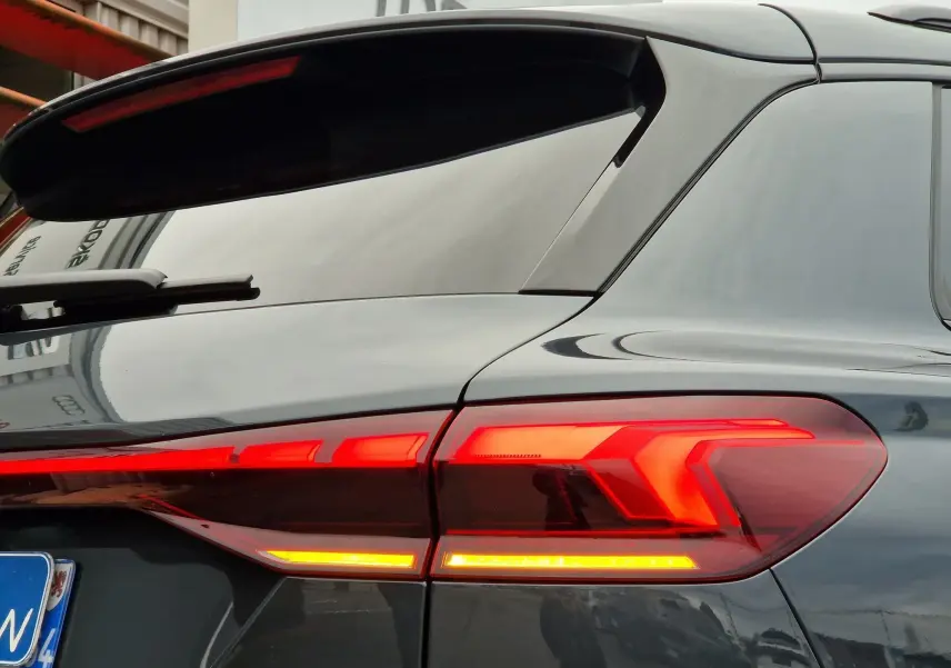 Gros plan sur le feu arrière droit rouge allumé de l'Audi Q6 e-tron Performance S-Line gris Manhattan 2025.