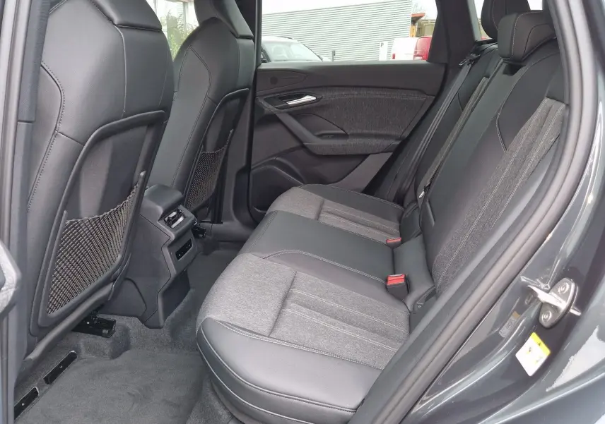 Vue intérieure côté gauche des sièges arrière en cuir et tissu gris d’un Audi Q6 e-tron Performance S-Line gris Manhattan 2025.