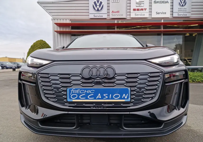 Vue frontale d'un Audi Q6 e-tron Performance S-Line gris Manhattan avec calandre hexagonale et logo Audi noir mat.