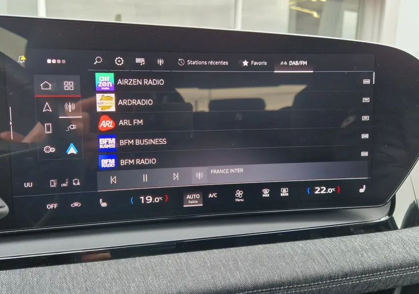 Écran tactile central de l’Audi Q6 e-tron Performance S-Line 2025, affichant les stations radio et la climatisation digitale.