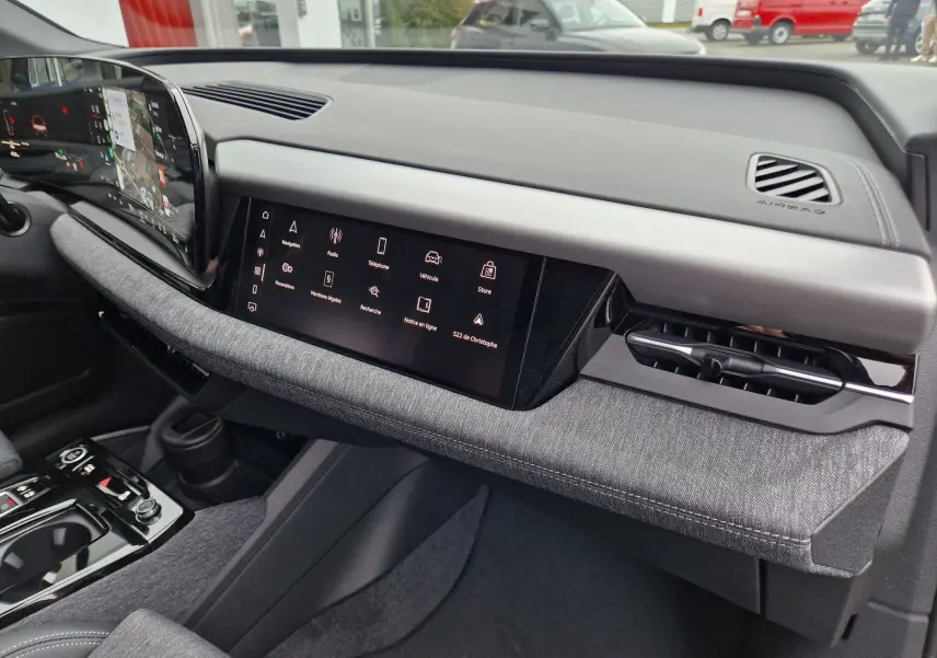 Vue intérieure du tableau de bord de l'Audi Q6 e-tron Performance S-Line 2025, avec écran tactile et finition grise Manhattan.