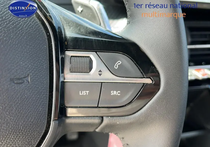 Gros plan sur les commandes gauche du volant noir du Peugeot 2008 1.2 hybrid 145 style e-dcs6, avec boutons multifonctions.