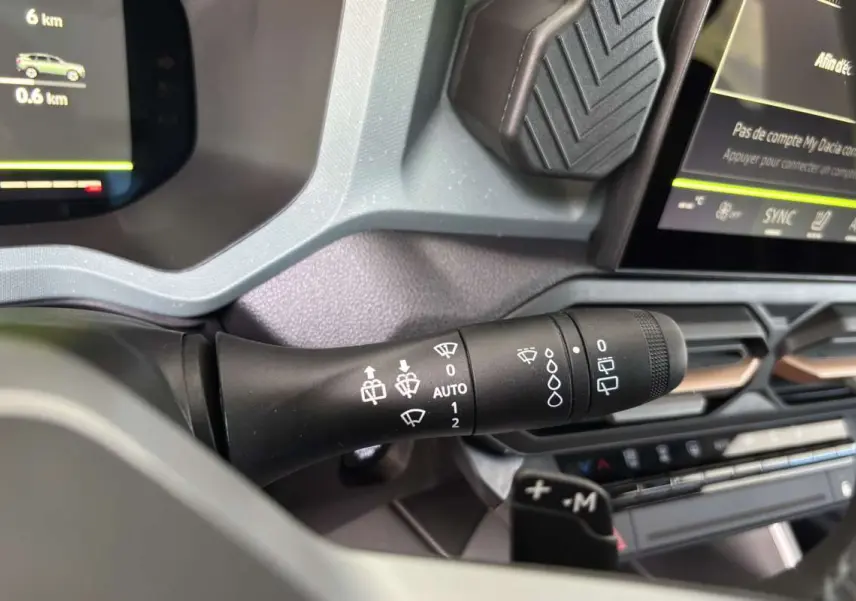 Gros plan sur la commande d’essuie-glace du tableau de bord du Dacia Bigster Hybrid-G 150 4x4 vert cèdre, intérieur moderne.