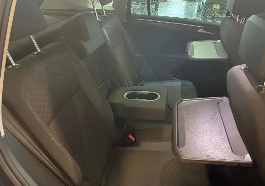 Vue intérieure sur les sièges arrière noirs du Volkswagen Tiguan 2020 avec tablettes rabattables et accoudoir central.