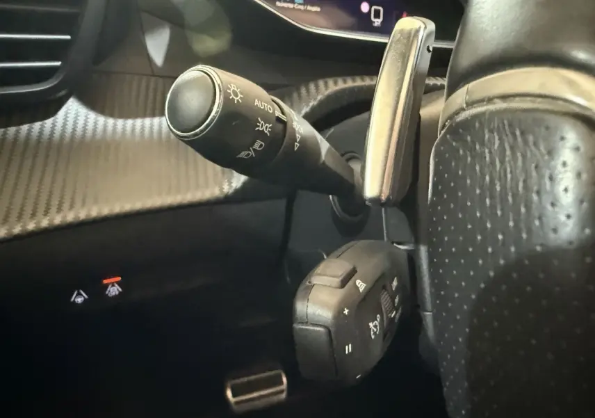 Gros plan sur la commande des phares et régulateur de vitesse du volant cuir perforé du Peugeot 2008 GT Pack 2021.