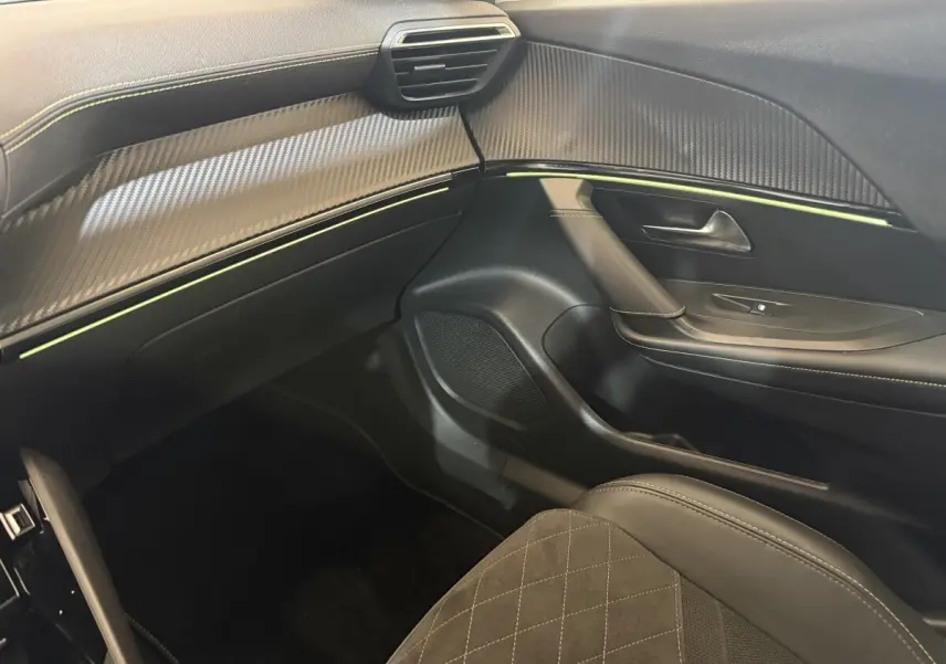 Vue intérieure côté passager du Peugeot 2008 GT Pack 2021, tableau de bord et porte avec surpiqûres et inserts carbone.