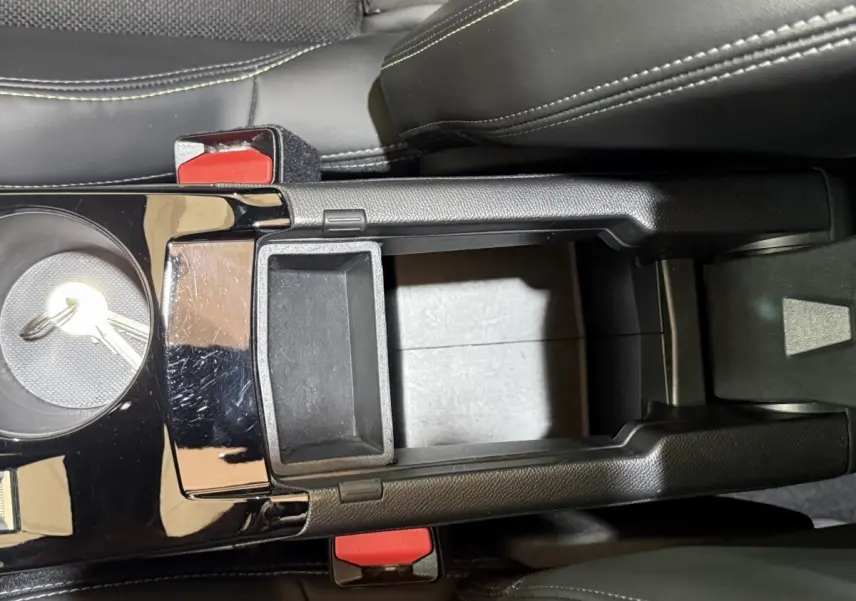 Vue plongeante sur la console centrale noire avec accoudoir ouvert et sièges en cuir noir du Peugeot 2008 bleu.