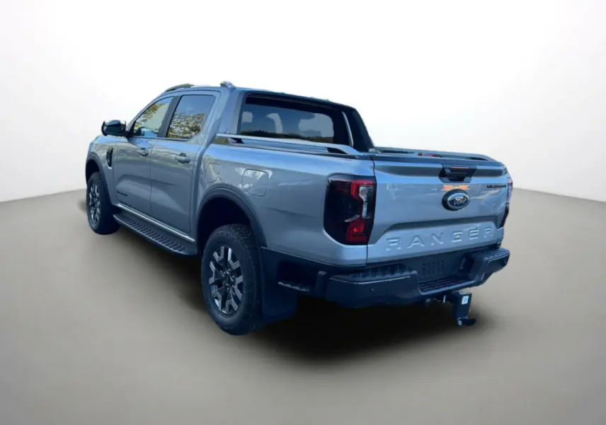 Ford Ranger PHEV gris iconic vu en 3/4 arrière droit avec attelage et barres de toit visibles.