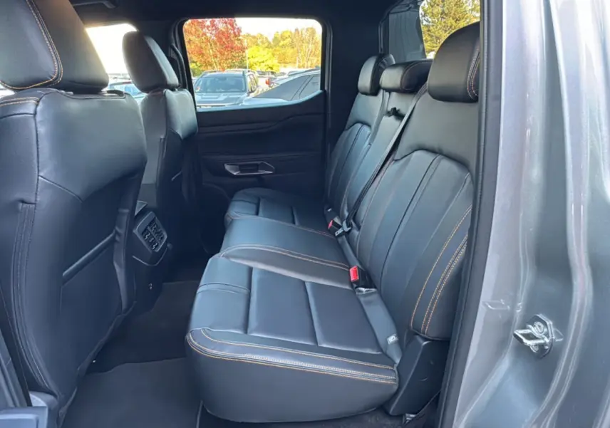 Vue intérieure côté droit des sièges arrière en cuir noir avec surpiqûres orange du Ford Ranger PHEV 281 Wildtrak gris iconic.