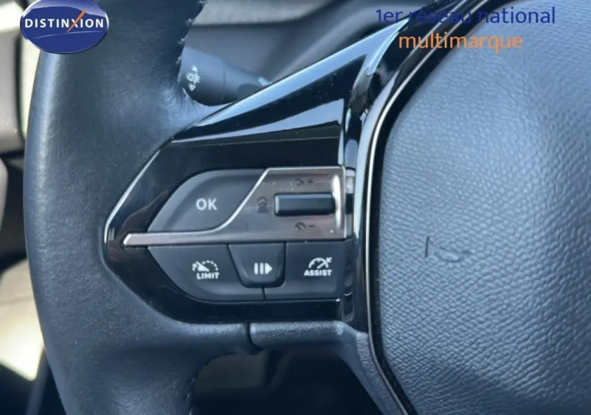 Gros plan sur le volant noir de la Peugeot 308 2021, avec commandes intégrées pour régulateur et limiteur de vitesse.