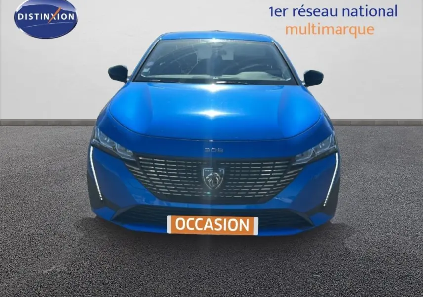 Vue frontale d'une Peugeot 308 bleu clair 2021 avec calandre moderne et feux LED verticaux allumés.